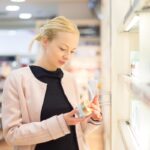femme lisant letiquette dun produit cosmetique dans un magasin