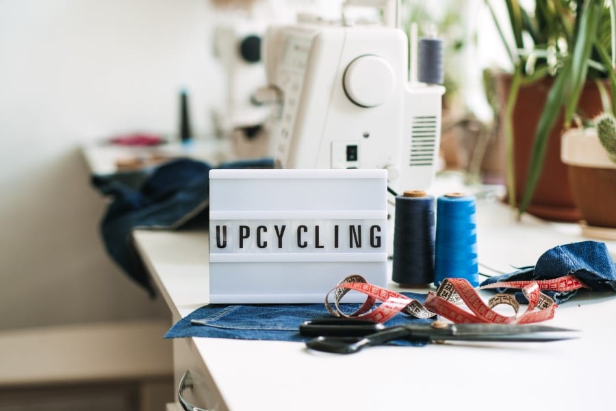 Upcycling sign next to fabrics and a sewing machine